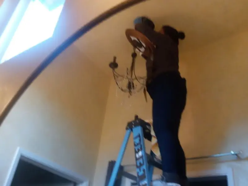 Electrician installing a chandelier in a Port Arthur residence